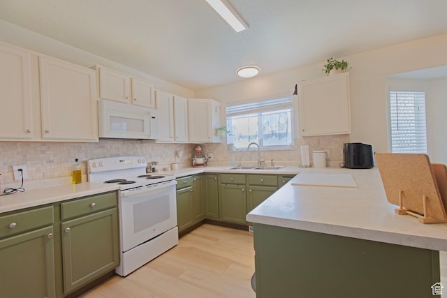 kitchen with green cabinetry, white appliances, a sink, a peninsula, and tasteful backsplash