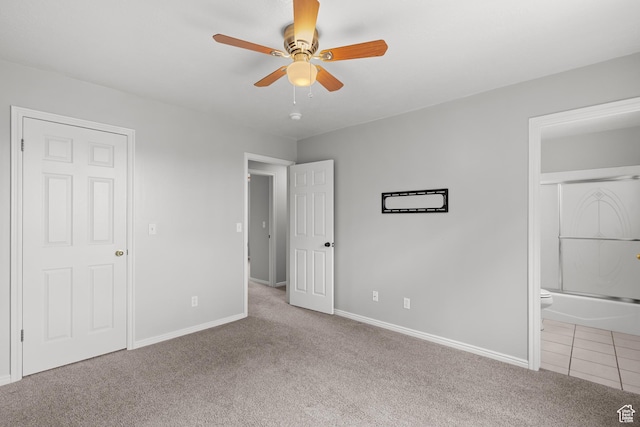 unfurnished bedroom with carpet flooring, ensuite bath, baseboards, and a ceiling fan