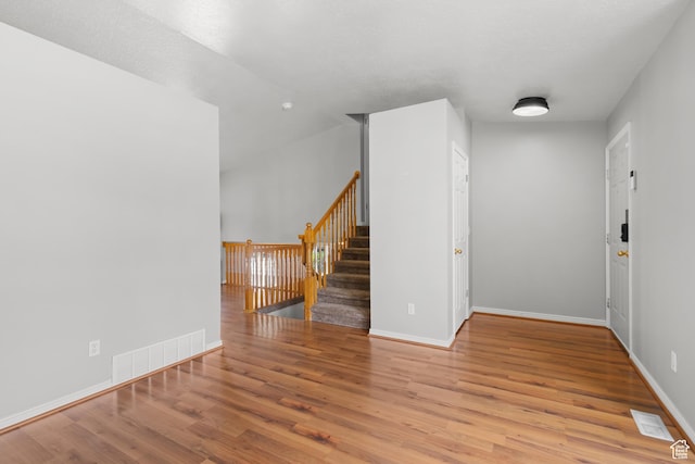 unfurnished room with wood finished floors, baseboards, and stairway