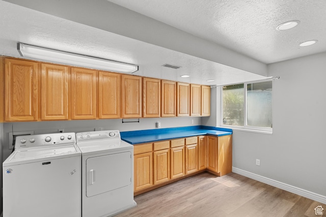 laundry room with washer and clothes dryer, a textured ceiling, cabinet space, light wood-style flooring, and baseboards
