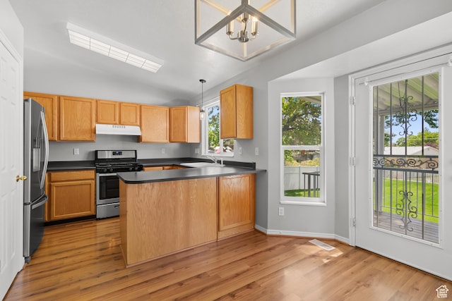 kitchen with stainless steel appliances, under cabinet range hood, a peninsula, dark countertops, and light wood-style floors