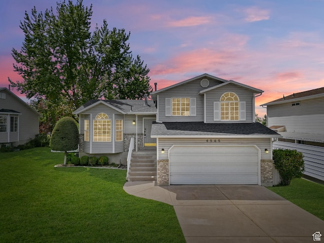 split level home with a garage, driveway, a yard, and roof with shingles