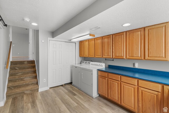 laundry area with independent washer and dryer, cabinet space, light wood finished floors, a textured ceiling, and baseboards