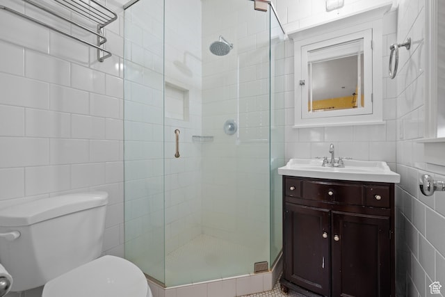 bathroom with tile walls, a stall shower, toilet, and vanity