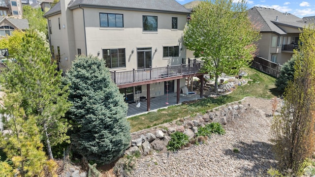 rear view of property with stucco siding, a wooden deck, a patio, and stairs