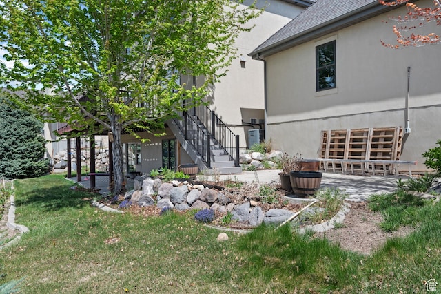 view of property exterior with stucco siding, stairway, a patio, a lawn, and an attached garage