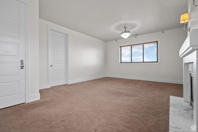 unfurnished living room with carpet floors, baseboards, and a fireplace with flush hearth
