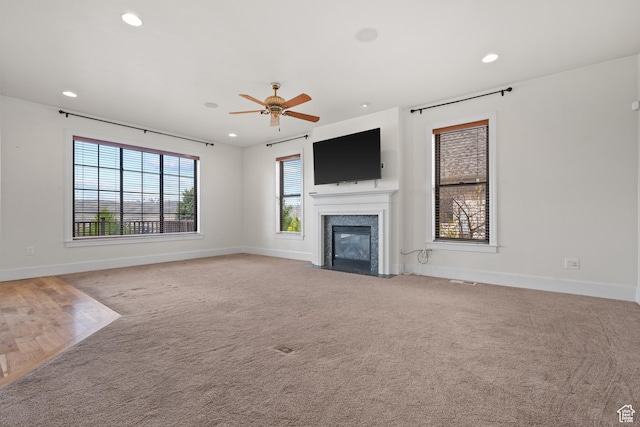 unfurnished living room with ceiling fan, baseboards, a fireplace with flush hearth, recessed lighting, and light carpet