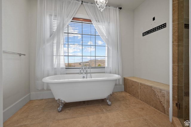 full bathroom featuring plenty of natural light, a soaking tub, tile patterned floors, and a chandelier