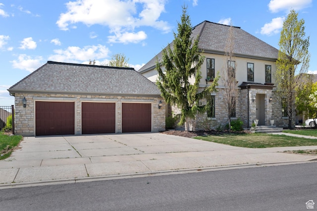 french country style house featuring concrete driveway, an attached garage, stone siding, and stucco siding