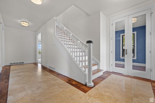foyer with french doors, healthy amount of natural light, stairway, and baseboards