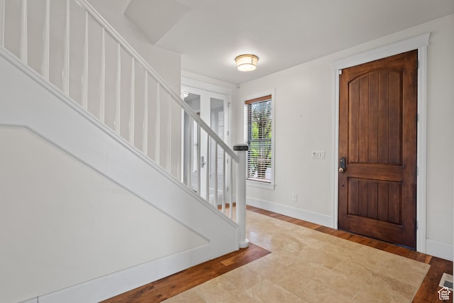 entrance foyer with stairway, wood finished floors, and baseboards