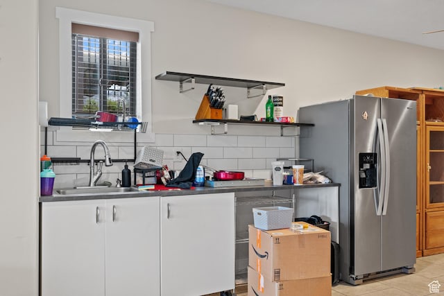 kitchen featuring stainless steel fridge, open shelves, a sink, backsplash, and white cabinetry