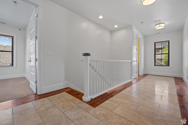 corridor featuring tile patterned floors, plenty of natural light, baseboards, and recessed lighting