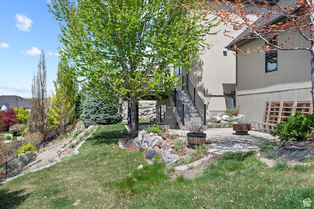 view of green lawn featuring stairs and a patio