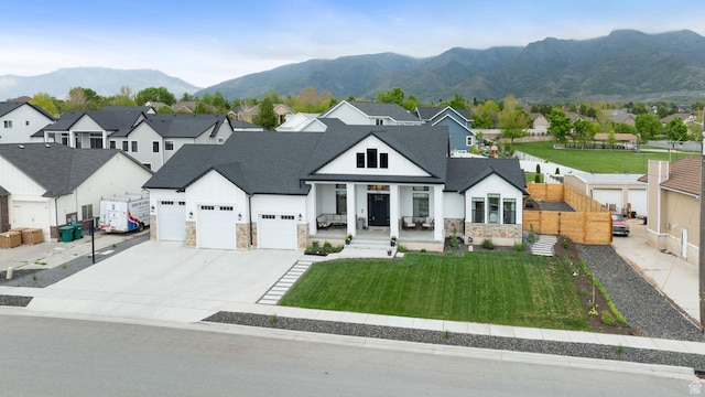 modern farmhouse featuring stone siding, a residential view, concrete driveway, a garage, and a mountain view