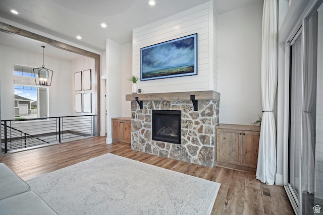 living room featuring wood finished floors, a chandelier, recessed lighting, and a stone fireplace
