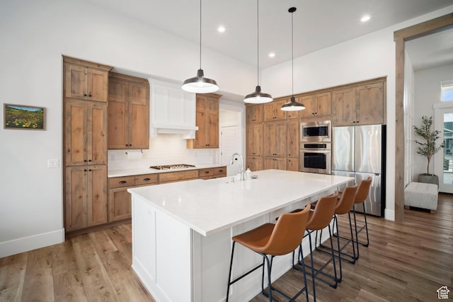 kitchen with appliances with stainless steel finishes, brown cabinets, light wood-type flooring, backsplash, and recessed lighting