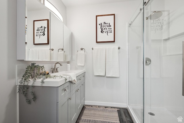 bathroom with a shower stall, baseboards, vanity, and wood finished floors
