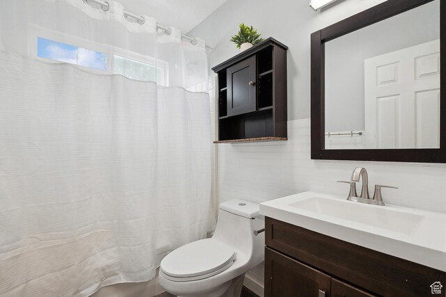 bathroom featuring toilet, vanity, and curtained shower