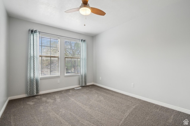 carpeted spare room featuring a ceiling fan and baseboards