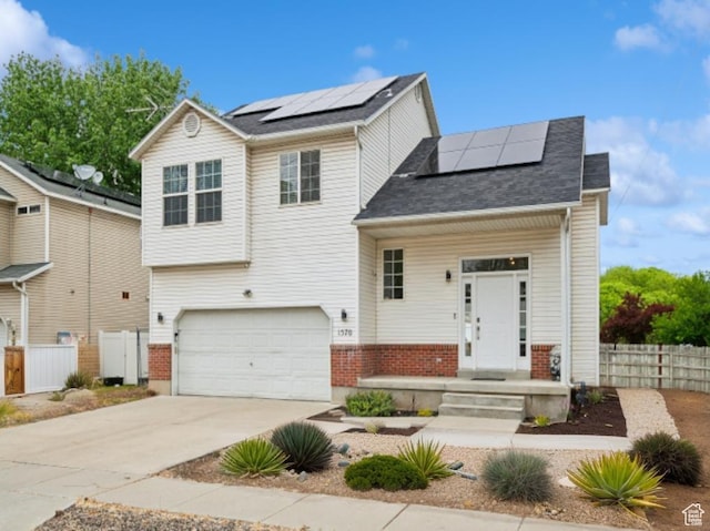 view of front of house with solar panels, fence, an attached garage, and driveway