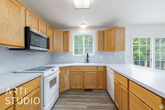kitchen featuring white appliances, a sink, light countertops, tasteful backsplash, and light wood-style floors