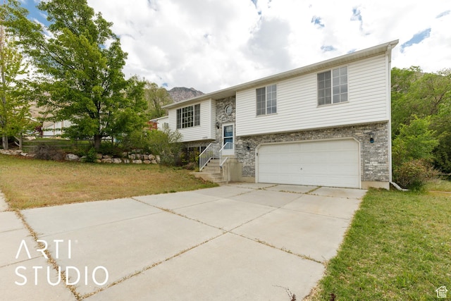 split foyer home featuring a garage, concrete driveway, and a front lawn
