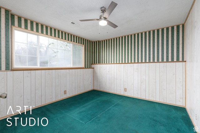 carpeted empty room with a ceiling fan and wallpapered walls