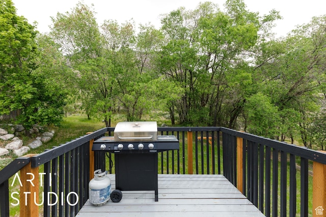 wooden terrace with area for grilling and view of scattered trees