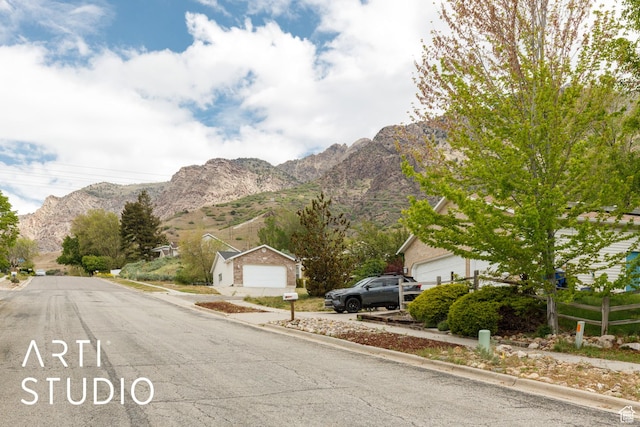 view of asphalt road featuring a mountain view and curbs