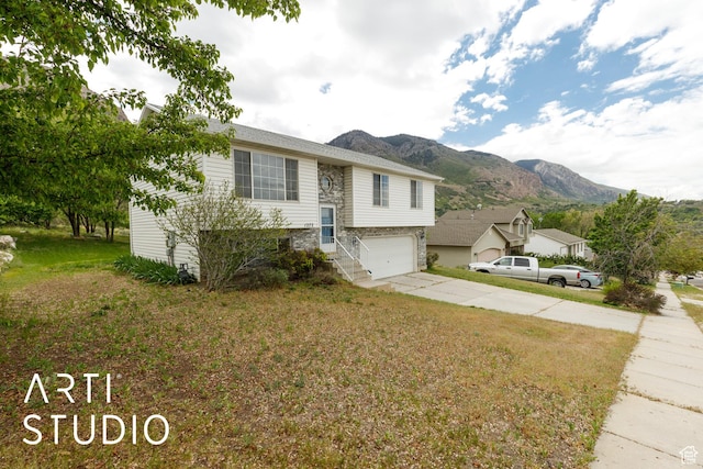 view of front of house featuring a mountain view, concrete driveway, a garage, and a front yard