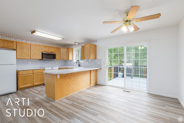 kitchen with freestanding refrigerator, stainless steel microwave, light countertops, a peninsula, and light wood-type flooring