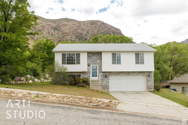 split foyer home with a mountain view, concrete driveway, and a garage