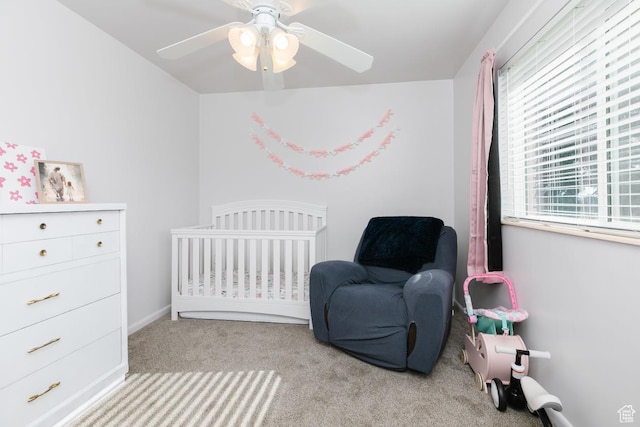 bedroom featuring carpet floors, a nursery area, ceiling fan, and baseboards