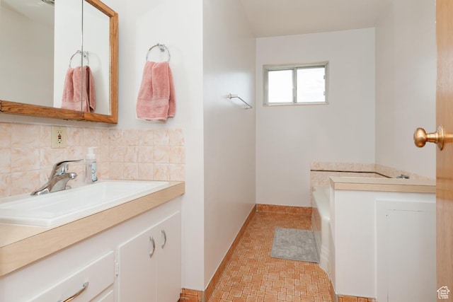 bathroom with decorative backsplash, vanity, a garden tub, and baseboards