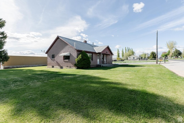 view of home's exterior featuring a lawn, metal roof, and a chimney