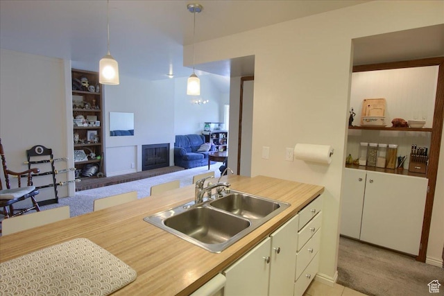 1091 Country Hills Dr Unit 306, Ogden, UT 84403 - kitchen with a sink, light countertops, a brick fireplace, decorative light fixtures, and light carpet