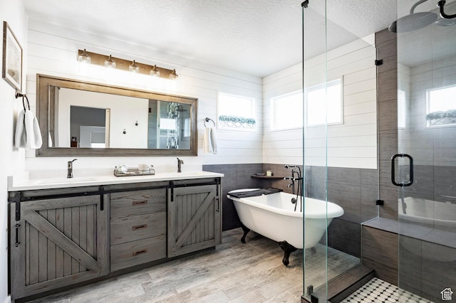 4468 W Meadow Bend Dr S, Herriman, UT 84096 - bathroom featuring a stall shower, double vanity, a freestanding bath, a textured ceiling, and tile walls