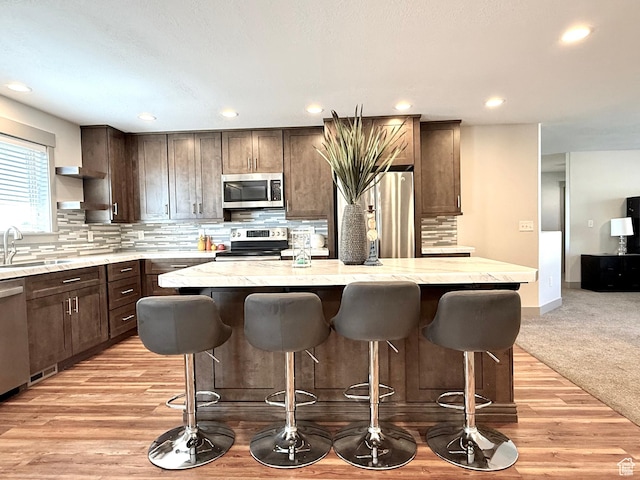 kitchen with appliances with stainless steel finishes, a sink, dark brown cabinetry, a center island, and recessed lighting