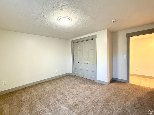 unfurnished bedroom featuring carpet flooring, a textured ceiling, baseboards, and a closet