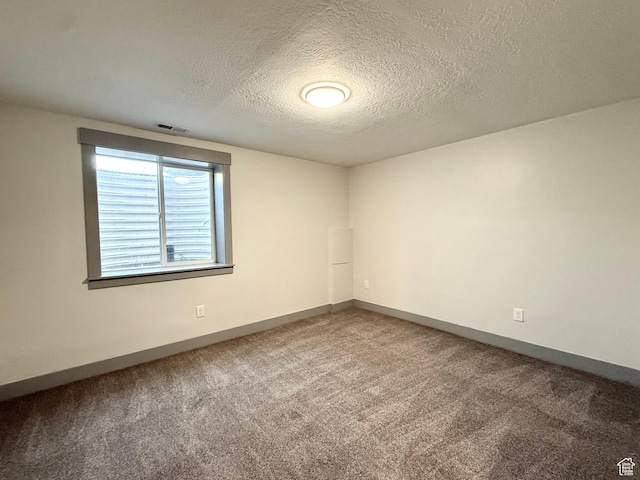 carpeted spare room with a textured ceiling and baseboards