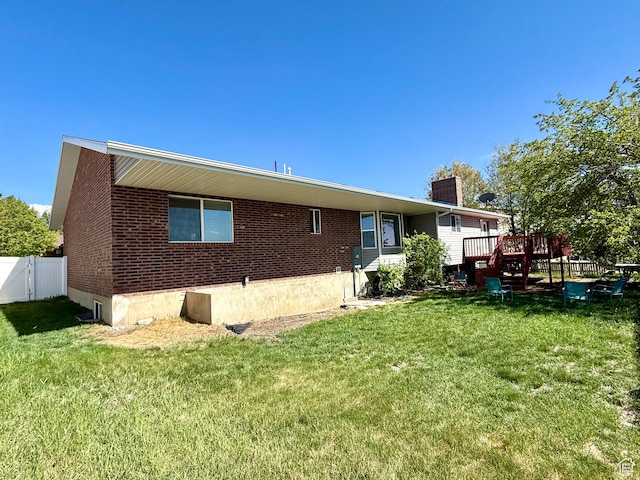 back of property featuring a wooden deck, a chimney, and brick siding