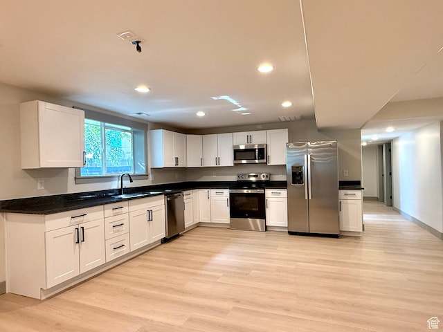 kitchen with stainless steel appliances, a sink, light wood-style floors, recessed lighting, and white cabinetry