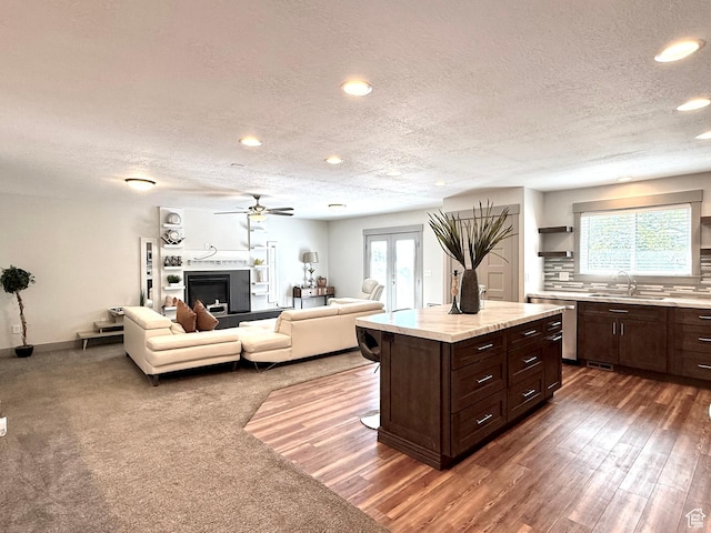 kitchen with a sink, recessed lighting, a textured ceiling, stainless steel dishwasher, and light countertops