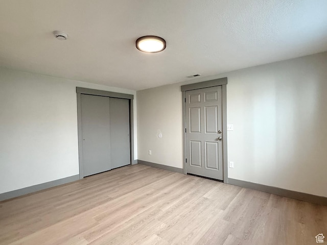 unfurnished bedroom with light wood finished floors, a closet, and baseboards