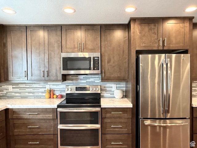 kitchen featuring stainless steel appliances, backsplash, dark brown cabinets, and recessed lighting