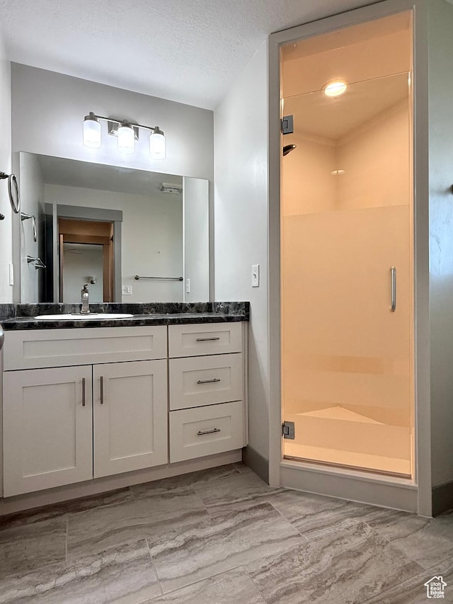 bathroom with a shower stall and vanity