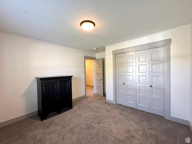 unfurnished bedroom with carpet flooring, baseboards, and a closet