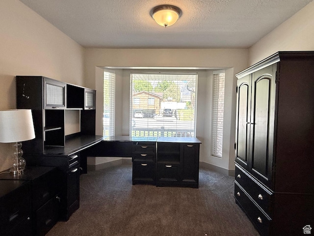 office area featuring dark colored carpet, baseboards, and a textured ceiling